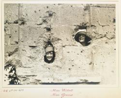deux autres jeunes femmes, tout aussi heureuses et même hilares, passent leur tête dans les trous faits par des obus dans un mur.