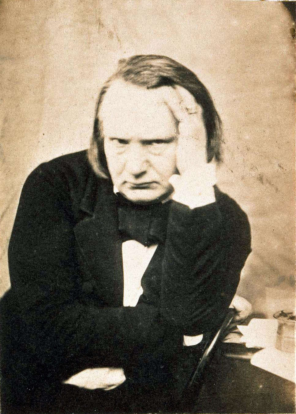 Victor Hugo assis, la main gauche à la tempe.