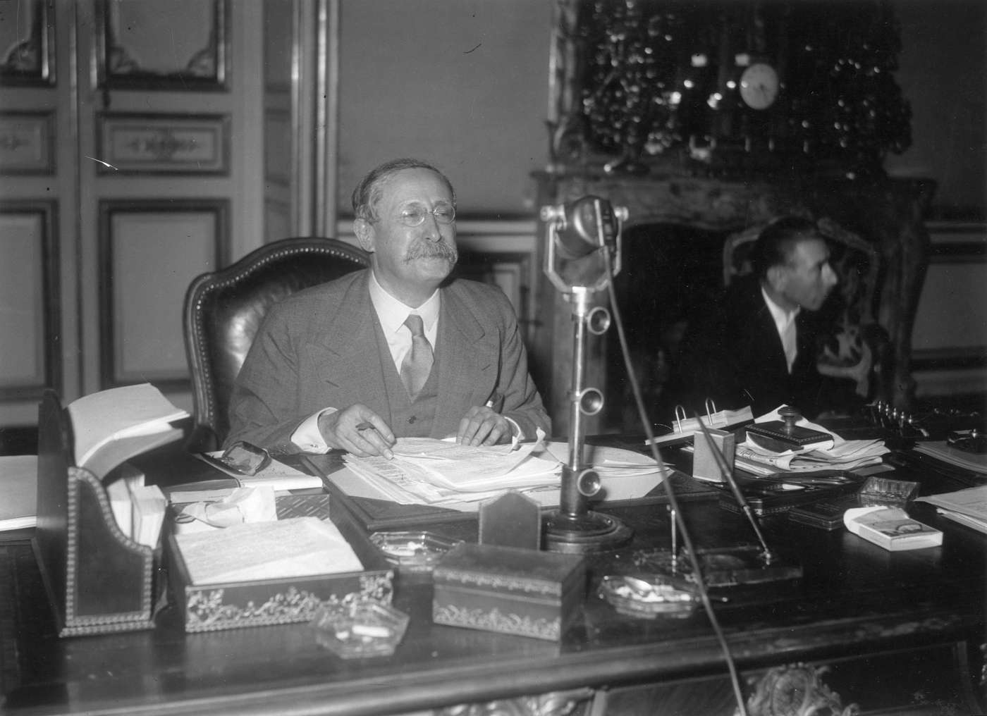 Léon Blum à son bureau de Matignon devant un micro de radio.