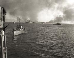 Des Chasseurs de sous marins et des Dragueurs de l'US Navy en action. Au loin, la pinede en feu plage de la Nartelle (Var) et les fumees de depots de munitions sous le feu des navires de la flotte alliee