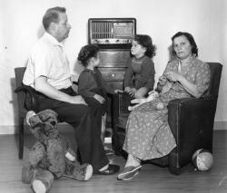 Une famille devant un poste de radio