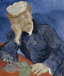 Un homme, médecin, en bleu avec une casquette, son coude posé sur une table rouge